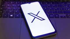 X logo displayed on a smartphone lying on a laptop keyboard