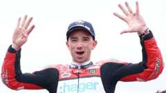 Glenn Irwin in a celebratory pose with his hands raised and a smile on his face