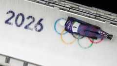 Matt Weston competing in the heats of the men's skeleton. On the ice behind him on the track is the Olympics logo and the writing '2026'