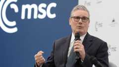 Starmer holding a microphone as he speaks on stage at the security conference