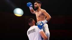 Hassan Ishaq is lifted up by his trainer in celebration