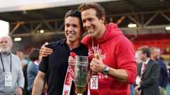 Wrexham co-owners McElhenney (left) and Ryan Reynolds (right) hold a League One promotion trophy