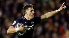 Scottish rugby player with ball in hand celebrates before scoring