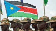 A blurry image of South Sudanese soldiers parading with their national flag.