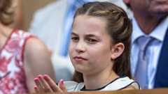 Princess Charlotte ina white dress sits among others