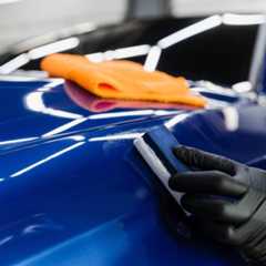 Process of applying ceramic protective coat on body car using sponge in detailing auto service. Car service worker apply ceramic coating to protect the car body from scratches. Ein Autoaufbereiter trägt mit einem Schwamm eine Keramikschutzschicht auf die Karosserie eines blauen Autos auf.