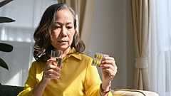 Eine Frau hält Vitamintabletten und eine Wasserflasche.