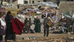 A Palestinian man carries bags of firewood after collecting them from the rubbish in Khan Younis, southern Gaza Strip, on Saturday, Nov. 15, 2025.