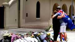 A couple lay flowers at a tribute to shooting victims outside the Bondi Pavilion at Sydney's Bondi Beach, Monday, Dec. 15, 2025, a day after a shooting. (AP Photo/Mark Baker)