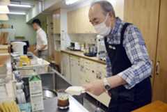 左手だけを使ってグラスに氷を入れる加藤修治さん=2025年10月、名古屋市