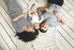 Young father, mother and cute baby lying on floor