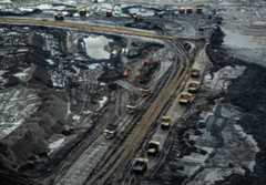 Huge trucks, some filled with oil sand and others awaiting filling, in a tar sands mine outside Fort McMurray, Alberta, Canada. From the mining operation, the sand is taken to a facility where the bitumen is separated from the sand. Credit: Michael Kodas/Inside Climate News