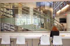 A student studies at the bar seating area of Whispers Cafe with a view of the Newman Tower stairs in the background.