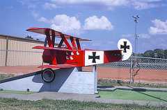 Color photo shows a small airplane painted red with two black crosses.