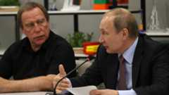 Photo of Roldugin looking on as Putin speaks
