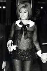 Black and white photograph of Barbra Streisand wearing a sparkly jumpsuit with a large bow around her neck