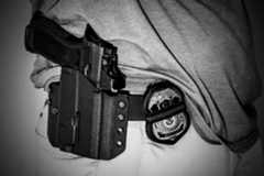 A person wears a holster belt with a gun.