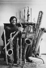 Portrait of musician and composer John Williams with a collection of brass instruments circa 1965.