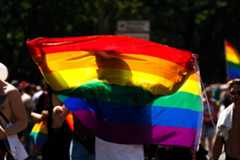Silhouette of a person behind a pride flag during a pride parade