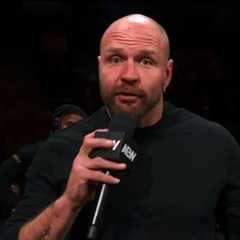 Jon Moxley delivering a promo on AEW Collision, holding a microphone while speaking to the audience. The background includes fans watching attentively.