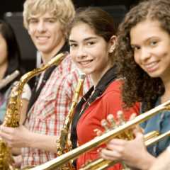 Teenage girl playing saxophone in band Teenage students holding saxophones