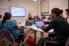 A classroom full of students around a table with computers in the Master of Science in business program