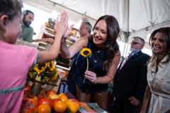 Secretary of Agriculture Brooke Rollins greets a girl who sold her a flower at a vendor at the inaugural Great American Farmers Market on the National Mall on  Aug. 4. Health and Human Services Secretary Robert F. Kennedy Jr. is behind her.