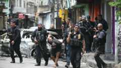 Des policiers escortent un suspect arrêté lors d'une opération dans la favela de Vila Cruzeiro, dans le complexe de Penha, à Rio de Janeiro, le 28 octobre 2025 au Brésil.