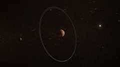 An artist illustration of the Quaoar system in front of a background of white stars. Central in the figure sits a brownish planet. This is Quaoar, a dwarf planet in the outer Solar System. At a distance of about five times its radius sits a ring. This ring is made up out of small grey pieces of debris. At twice the distance of the ring, to the left of Quaoar, sits its moon Weywot. Weywot looks about a sixth the size of Quaoar but has the same brownish colour. To the right of this system, we see a bright star. This star is bigger than the background stars and represents the distant Sun