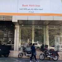 An Iranian woman walks past a branch of the state-owned Melli Bank, which absorbed the assets of the now-defunct Ayandeh Bank, with signage on its facade reading in Farsi "This former Ayandeh Bank branch is now part of Melli Bank," in the capital Tehran on October 25, 2025. (ATTA KENARE / AFP) An Iranian woman walks past a branch of the state-owned Melli Bank, which absorbed the assets of the now-defunct Ayandeh Bank, with signage on its facade reading in Farsi "This former Ayandeh Bank branch is now part of Melli Bank," in the capital Tehran on October 25, 2025. (ATTA KENARE / AFP)