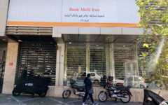 An Iranian woman walks past a branch of the state-owned Melli Bank, which absorbed the assets of the now-defunct Ayandeh Bank, with signage on its facade reading in Farsi "This former Ayandeh Bank branch is now part of Melli Bank," in the capital Tehran on October 25, 2025. (ATTA KENARE / AFP) An Iranian woman walks past a branch of the state-owned Melli Bank, which absorbed the assets of the now-defunct Ayandeh Bank, with signage on its facade reading in Farsi "This former Ayandeh Bank branch is now part of Melli Bank," in the capital Tehran on October 25, 2025. (ATTA KENARE / AFP)