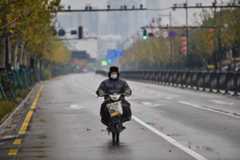 A man wearing a protective facemask rides a motorcycle on a street in Wuhan on Sunday. (AFP photo)