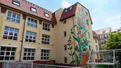 Gelbes Gebäude mit rotem Dach und bunter Wandmalerei