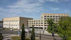 Schulgebäude mit Bäumen und einer Straße vorn