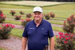 Walt Hitch in front of rose bushes