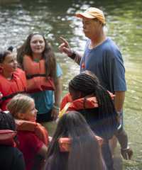 A group of 4-H campers stand in a stream