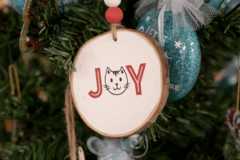 A round wooden Christmas ornament with the word