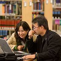 students working at laptop inside library