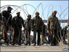 Indian police officials stand behind barbed wire blocking a road during a gunbattle in Srinagar - January 2010