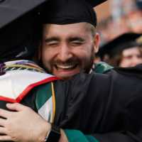 Two people in caps and gowns embrace.