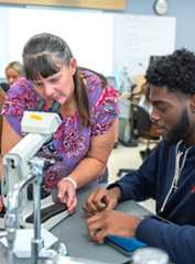 An instructor assisting a student with a microscope in a science laboratory at the Kent State University Geauga Twinsburg Academic Center.