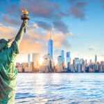 View of Statue of Liberty from back overlooking New York city skyline at sunset