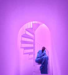 Close-up of a woman sitting on a spiral staircase demonstrating the pro camera system's low-light photographic capabilities