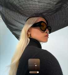 A portrait of a woman wearing a wide-brimmed black hat demonstrates the Bright Photographic Style, which brightens photos shot in low lighting conditions or Night mode