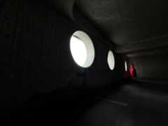 A woman wearing a long red dress stands in an empty room being photographed. The Photo app toggles through the focal lengths to demonstrate the capabilities of the pro camera system, showcasing: 13 mm