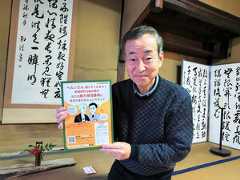 西田千太郎旧居の客間で修繕費を募るプロジェクトのチラシを手にする今岡克己さん=2026年2月9日午後5時25分、松江市新雑賀町、堀田浩一撮影