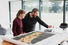 A man and woman collaborate over map data with computer