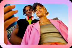 屋外で立ってスマートフォンの画面を見ている 2 人の若者の画像。