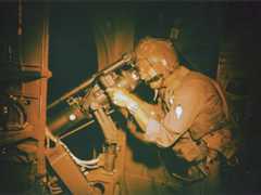 Photo of William Dawson of the 71st Special Operations Squadron trains his AC-119’s night observation scope during a mission in April 1969.