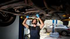 A mechanic working underneath a vehicle on a lift